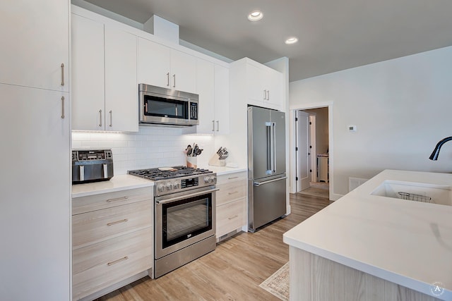 2800 Ashley Ave, East Helena, MT 59635 - kitchen featuring decorative backsplash, light wood-style floors, light countertops, a sink, and stainless steel appliances