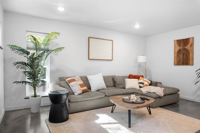 living area featuring baseboards, recessed lighting, and finished concrete flooring