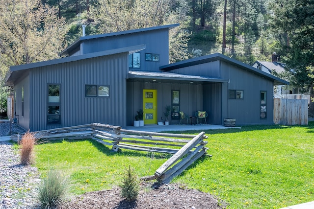 back of property featuring fence, covered porch, a yard, and metal roof