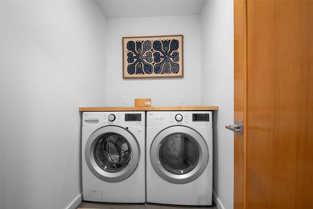 clothes washing area with separate washer and dryer, baseboards, and laundry area