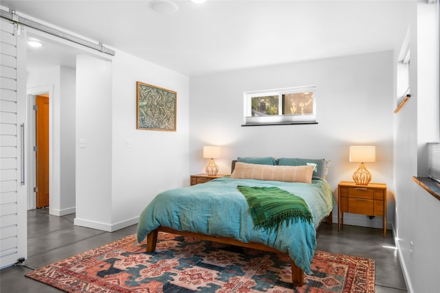 bedroom featuring concrete flooring, baseboards, and a barn door