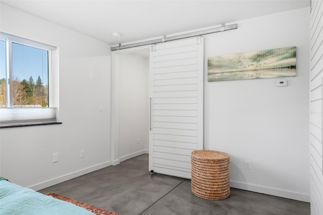 bedroom featuring baseboards, a barn door, and finished concrete floors