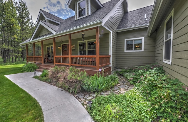 property entrance with a porch, a shingled roof, and a yard