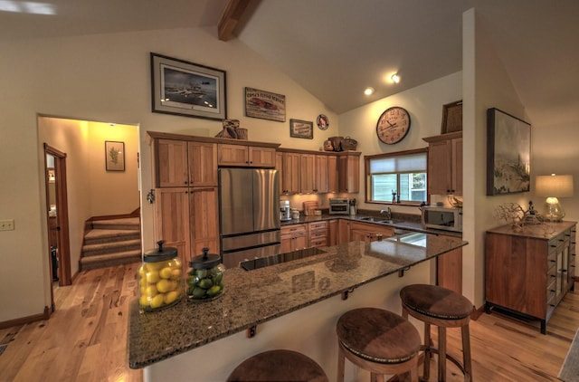 kitchen featuring a breakfast bar area, stainless steel appliances, high vaulted ceiling, and a sink