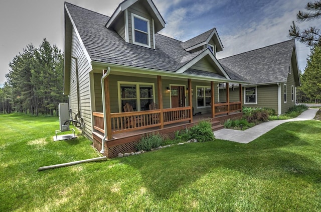 rear view of house featuring a lawn, covered porch, and roof with shingles