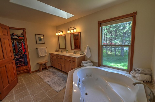 full bath with a skylight, double vanity, a whirlpool tub, and a sink