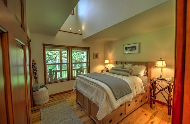 bedroom featuring baseboards, vaulted ceiling, and light wood-style floors