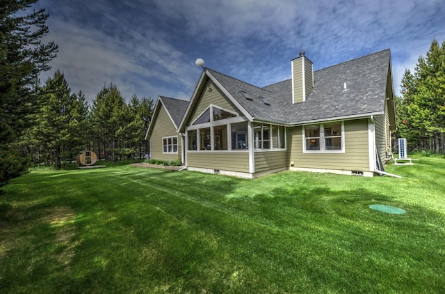 back of property featuring a lawn, a chimney, and roof with shingles