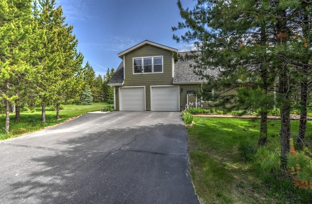 view of front of property featuring an attached garage, a shingled roof, driveway, and a front yard