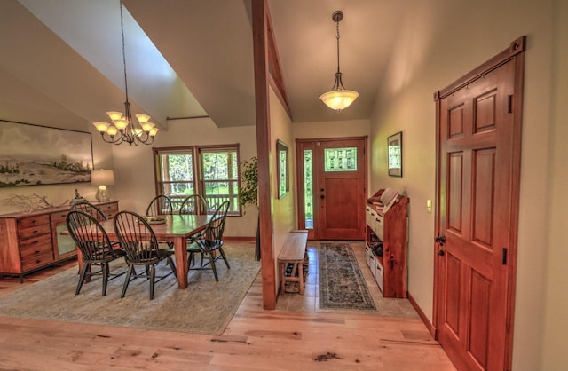 entryway with baseboards, vaulted ceiling, an inviting chandelier, and light wood-type flooring