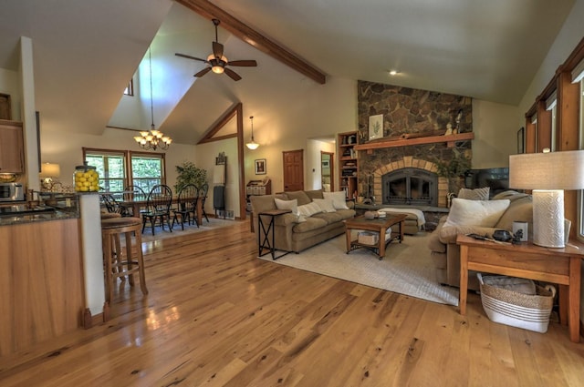 living room featuring a stone fireplace, high vaulted ceiling, beamed ceiling, ceiling fan with notable chandelier, and light wood-style floors