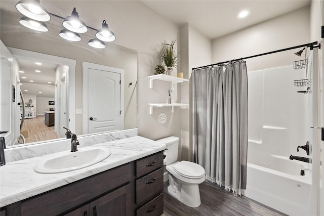 bathroom with shower / bath combo, wood finished floors, vanity, toilet, and recessed lighting