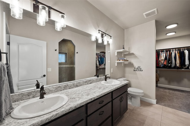 full bath featuring a sink, tile patterned floors, a walk in closet, and visible vents