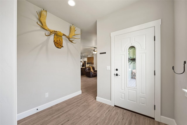 foyer featuring baseboards, ceiling fan, and wood finished floors