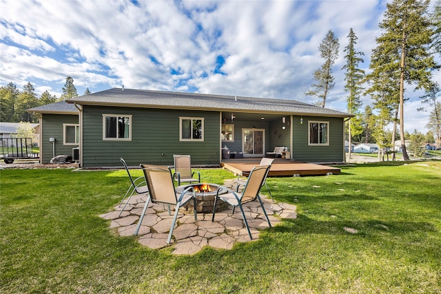 back of property with a lawn, a wooden deck, and an outdoor fire pit