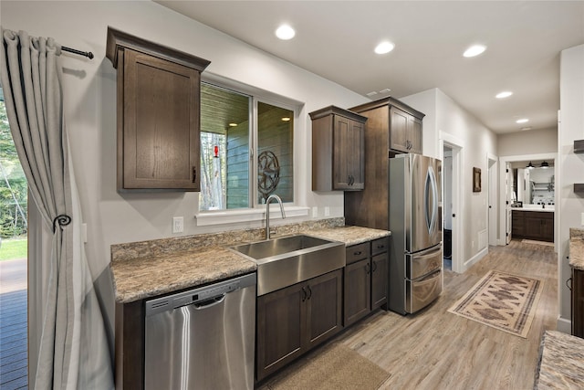 kitchen with a sink, appliances with stainless steel finishes, dark brown cabinetry, and light wood-style floors