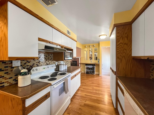 kitchen with dark countertops, light wood finished floors, white appliances, white cabinetry, and under cabinet range hood