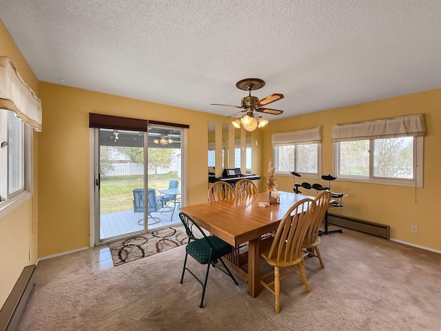 dining space featuring a textured ceiling, a baseboard heating unit, light carpet, and a wealth of natural light