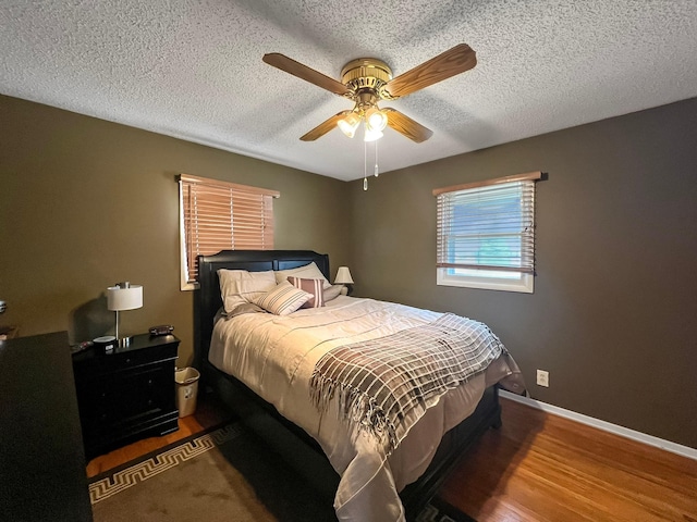bedroom featuring baseboards, a textured ceiling, ceiling fan, and wood finished floors
