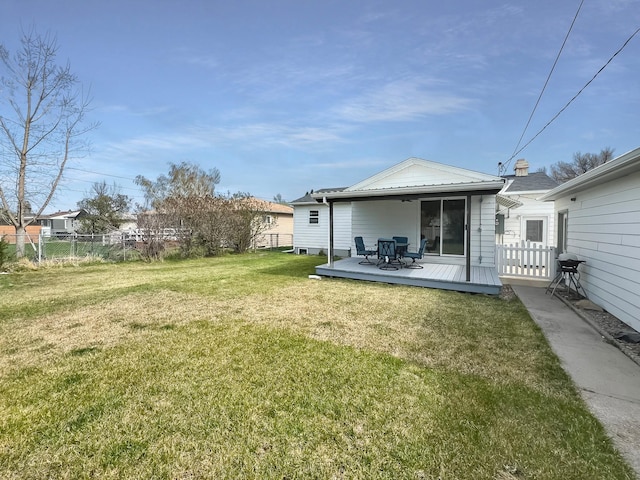 back of house featuring a lawn, a deck, and fence