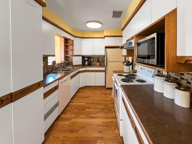 kitchen with white cabinets, a sink, white appliances, backsplash, and visible vents