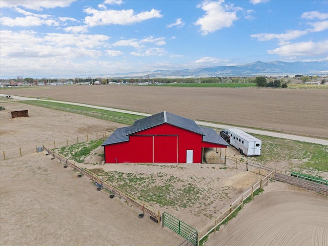view of pole building with a rural view, fence, and a mountain view