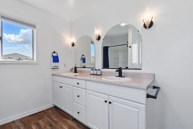 full bath with visible vents, a sink, wood finished floors, and double vanity
