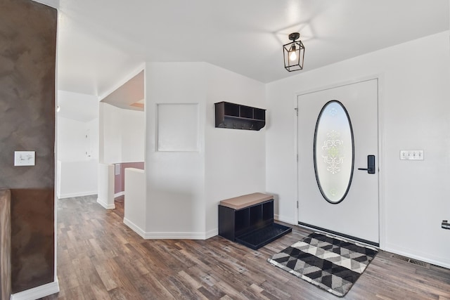 foyer with baseboards, visible vents, and wood finished floors