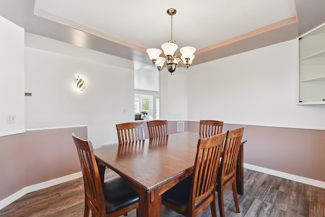 dining area with baseboards, an inviting chandelier, wood finished floors, and a tray ceiling