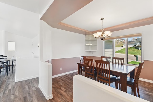 dining room with baseboards, a tray ceiling, dark wood-style floors, and a chandelier