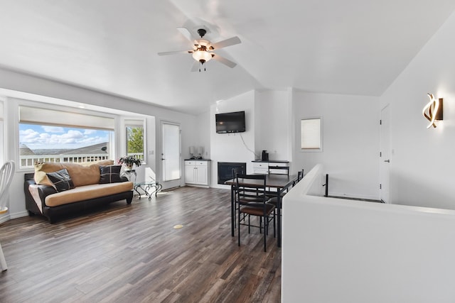 living room featuring baseboards, a ceiling fan, vaulted ceiling, and dark wood-style flooring