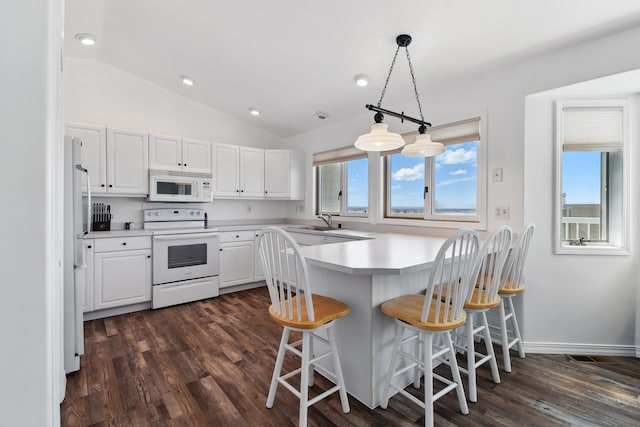 kitchen with a peninsula, white appliances, white cabinetry, and dark wood-type flooring