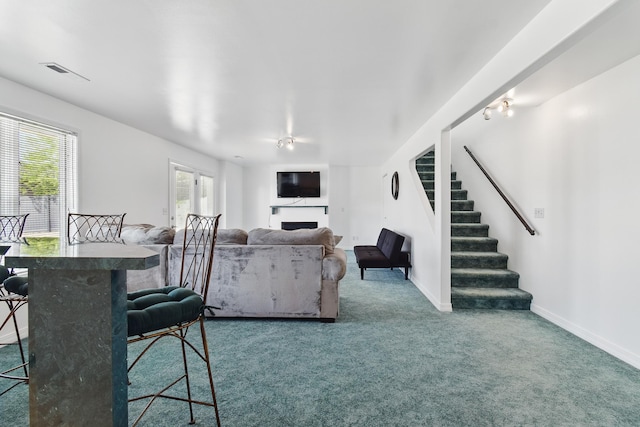 living room featuring a fireplace, carpet floors, stairs, baseboards, and visible vents