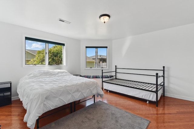 bedroom with baseboards, wood finished floors, and visible vents