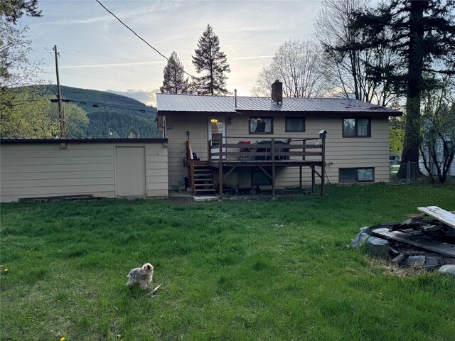 back of house featuring a deck with mountain view, a chimney, metal roof, a yard, and stairway