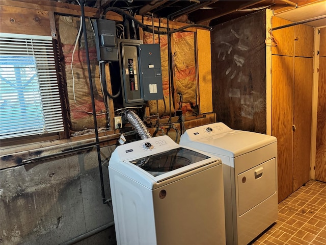 washroom with brick floor, electric panel, washing machine and dryer, and laundry area