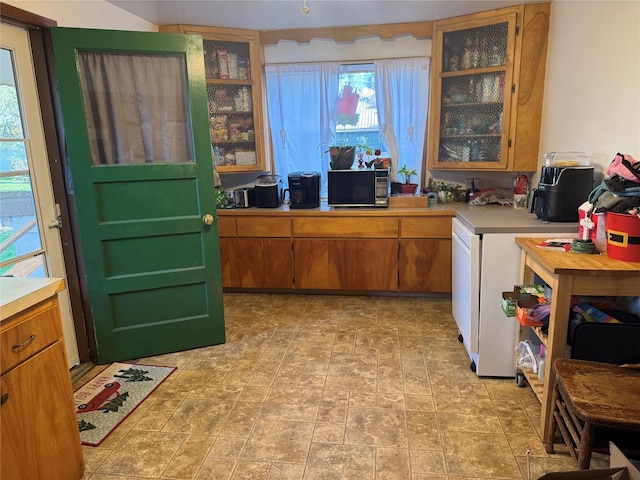 kitchen with black microwave, light countertops, brown cabinets, and glass insert cabinets
