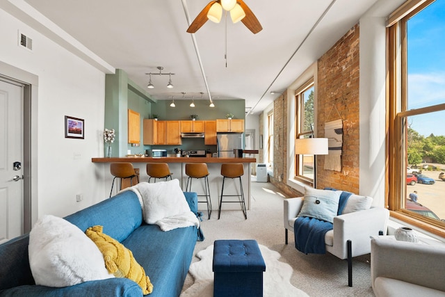 living area featuring visible vents, rail lighting, ceiling fan, and light carpet