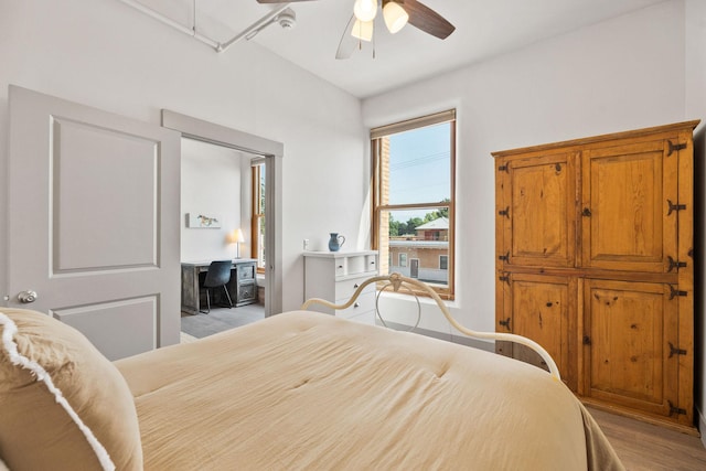 bedroom featuring light wood-style floors, attic access, and ceiling fan