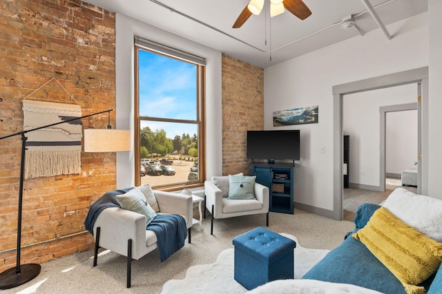 living room featuring carpet floors, ceiling fan, and brick wall