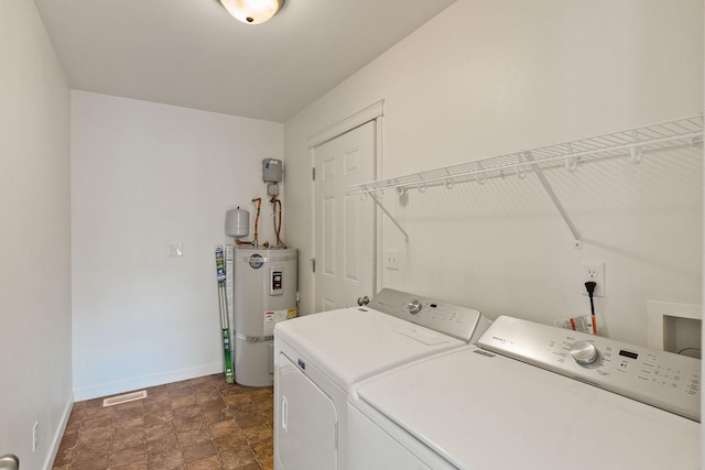clothes washing area with laundry area, visible vents, baseboards, secured water heater, and washer and clothes dryer