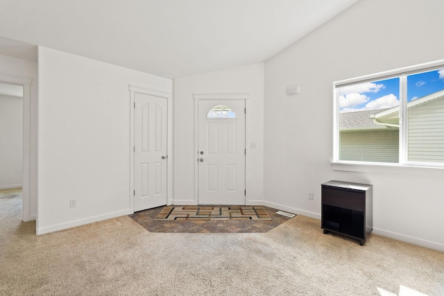 carpeted entryway featuring baseboards, visible vents, and lofted ceiling