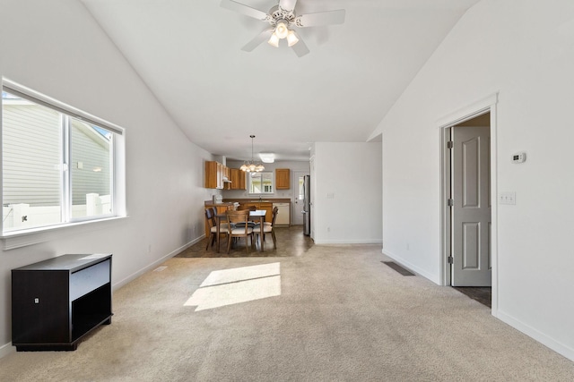 living area with light colored carpet, ceiling fan with notable chandelier, baseboards, lofted ceiling, and visible vents
