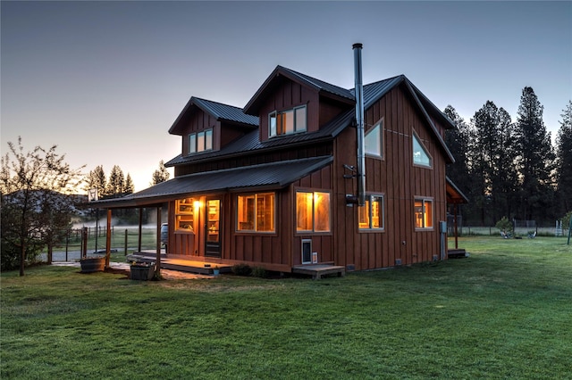 85 Martin Ln, Florence, MT 59833 - back of property at dusk with board and batten siding, a lawn, metal roof, and covered porch
