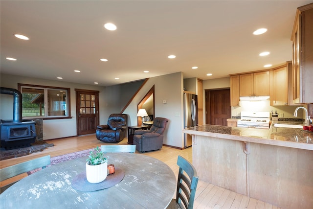 dining room featuring light wood-type flooring, a wood stove, and recessed lighting