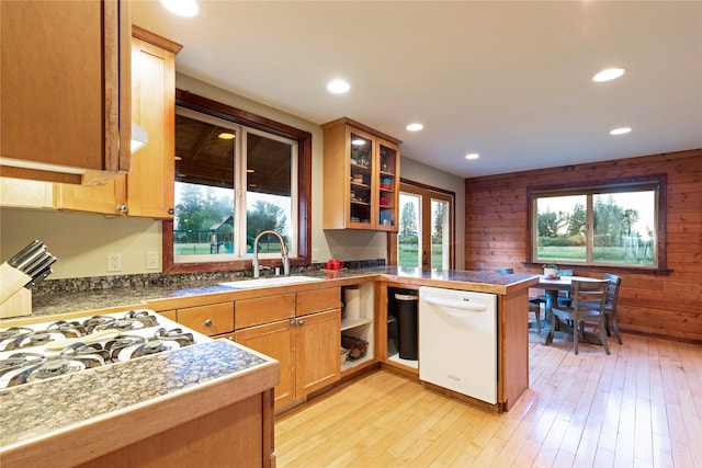 kitchen featuring a peninsula, light wood-type flooring, tile countertops, a sink, and dishwasher
