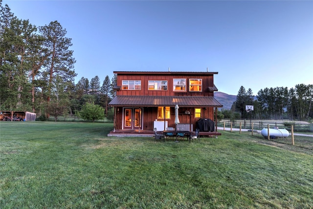 back of property featuring fence, board and batten siding, a yard, and metal roof