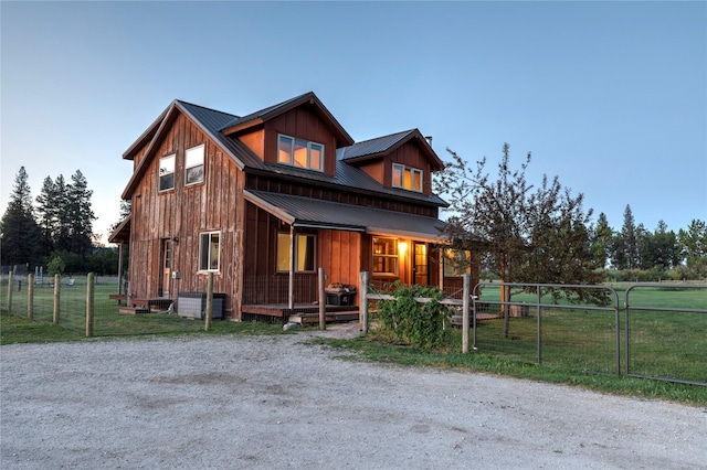 view of front of property featuring board and batten siding, fence, covered porch, and metal roof