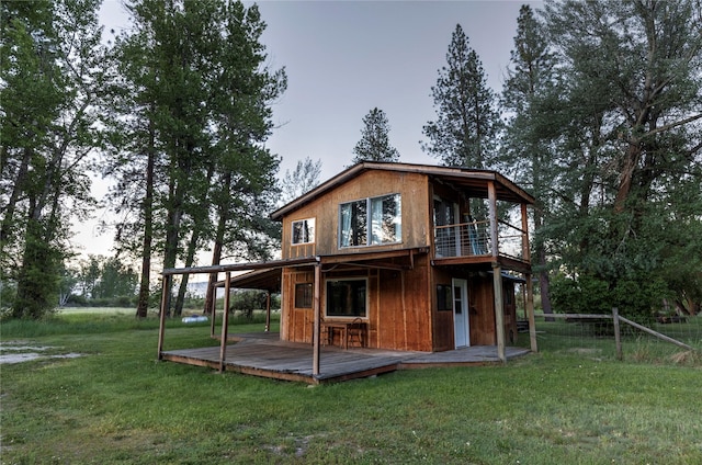 back of property with fence, a lawn, and a deck