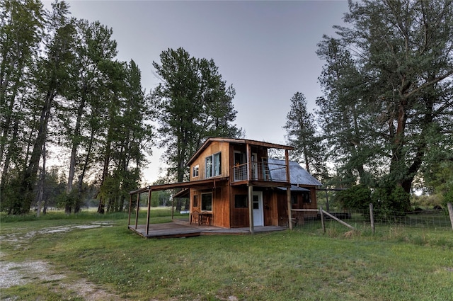 rear view of property featuring fence, a wooden deck, and a yard